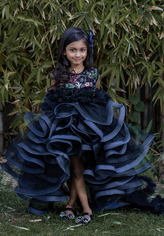 Black floral embroidered couture gown for girls with dramatic layered ruffles and high-low trail