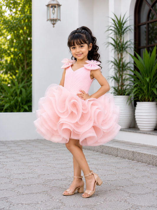 Blush pink couture party dress for girls with pearl embellished shoulder bows and dramatic layered ruffle skirt
