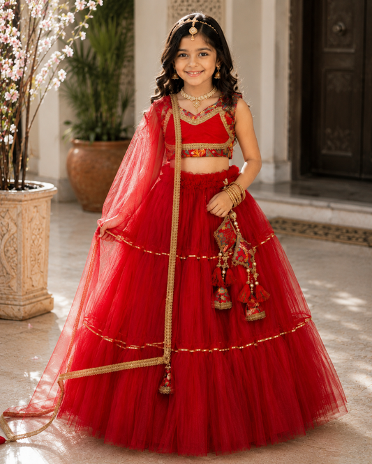 Premium red net layered lehenga choli set for girls with designer printed blouse, golden lace border dupatta, tassel accessories and festive ethnic styling.