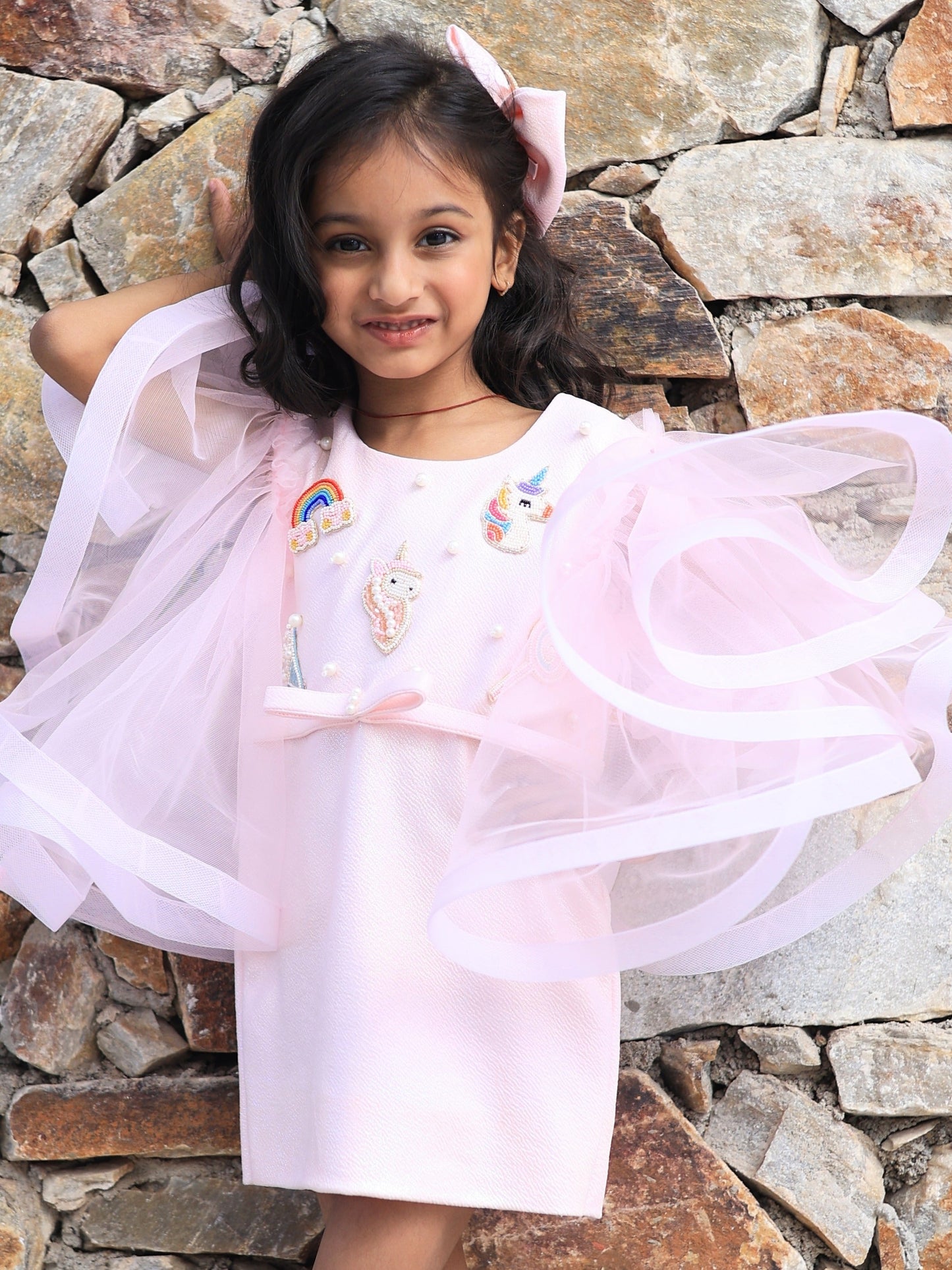 
Pink unicorn embroidered party dress for girls with dramatic flared sleeves and rainbow detailing 1